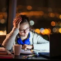 girl looking frustrated while studying at nighttime