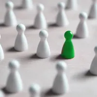 green pawn amid white pawns against white background