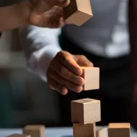 hands stacking building blocks