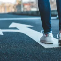 legs standing behind arrow on asphalt