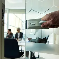 a hand opening a door to an occupied conference room