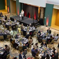Dinner guests seated with CEO Brittany Kauffman speaks on stage