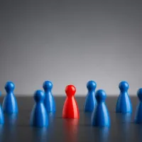 single red figure among blue group of pawns