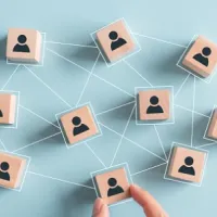 light wooden blocks with people painted on them, connected by lines, on light blue background