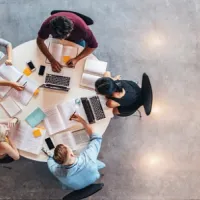aerial shot of five university students working at round table