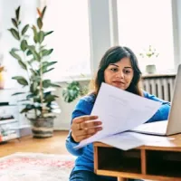 woman looking at laptop and papers