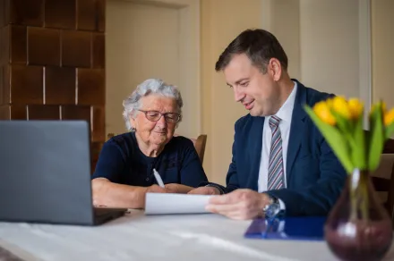 A lawyer meeting with a senior client to sign papers.