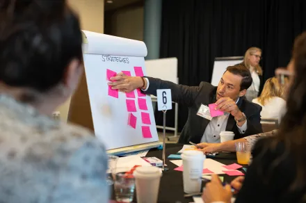 A man putting a sticky note on a display. 