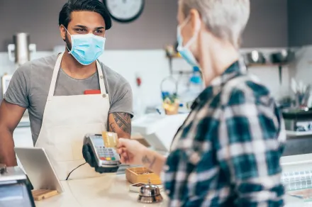 Masked merchant helping customer