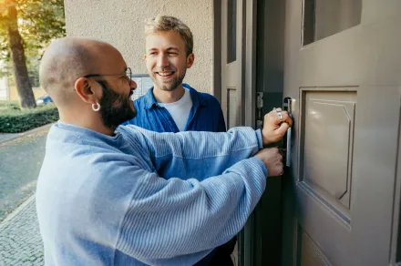 Two men unlocking a door together.