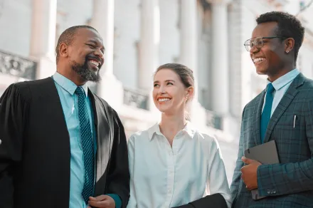 Three people smiling at a courthouse