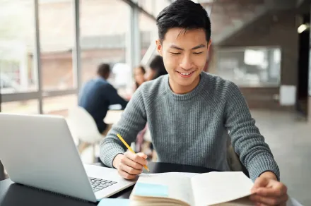 A law student studying from a book and laptop