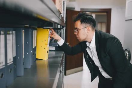Man removing binder of files from shelf
