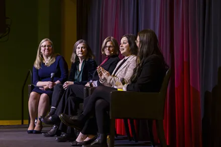 five people sitting on chairs on stage