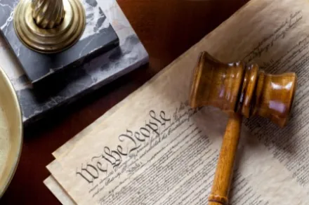 wooden gavel lying on top of U.S. Constitution
