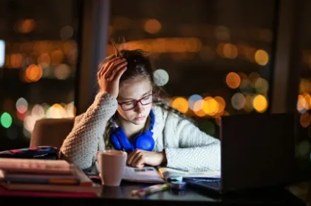 girl looking frustrated while studying at nighttime