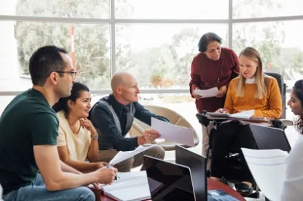 group of six people in a sunny room collaborating on a project