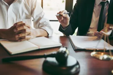 two people sitting at desk with gavel