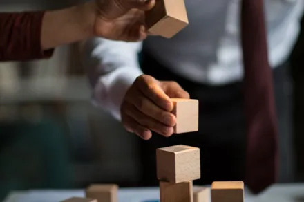 hands stacking building blocks