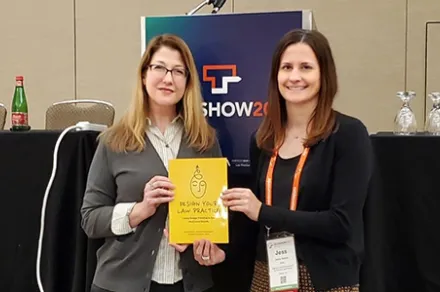 two women standing next to each other holding yellow book