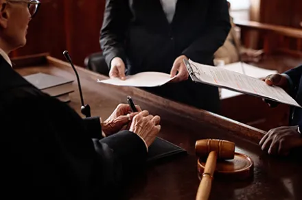 A judge conferring with two people in a courtroom