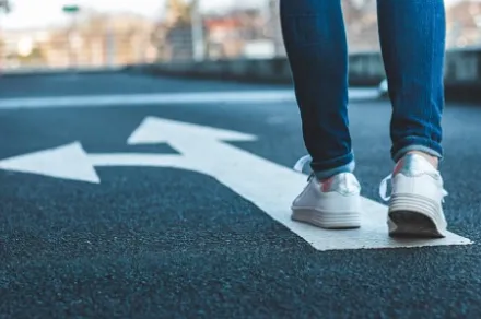 legs standing behind arrow on asphalt