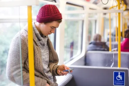 man using smartphone on bus