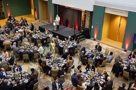 Dinner guests seated with CEO Brittany Kauffman speaks on stage