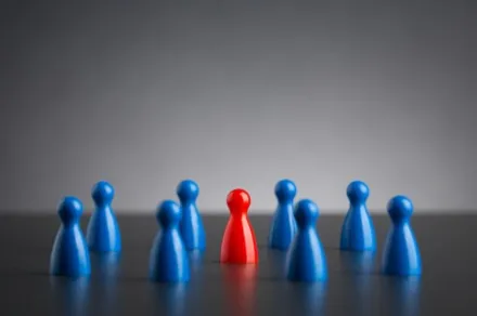 single red figure among blue group of pawns