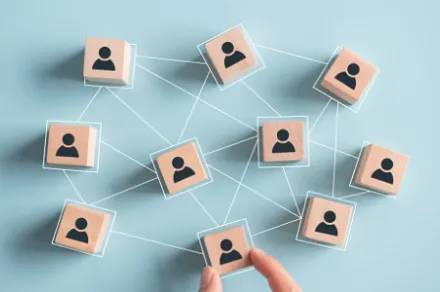 light wooden blocks with people painted on them, connected by lines, on light blue background