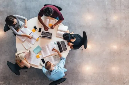 aerial shot of five university students working at round table