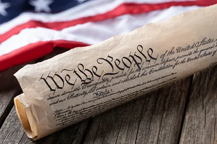 US Constitution rolled next to American flag
