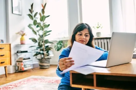 woman looking at laptop and papers