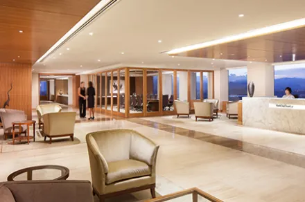 lobby with tile floors, armchairs, end tables, reception desk, and floor-to-ceiling windows